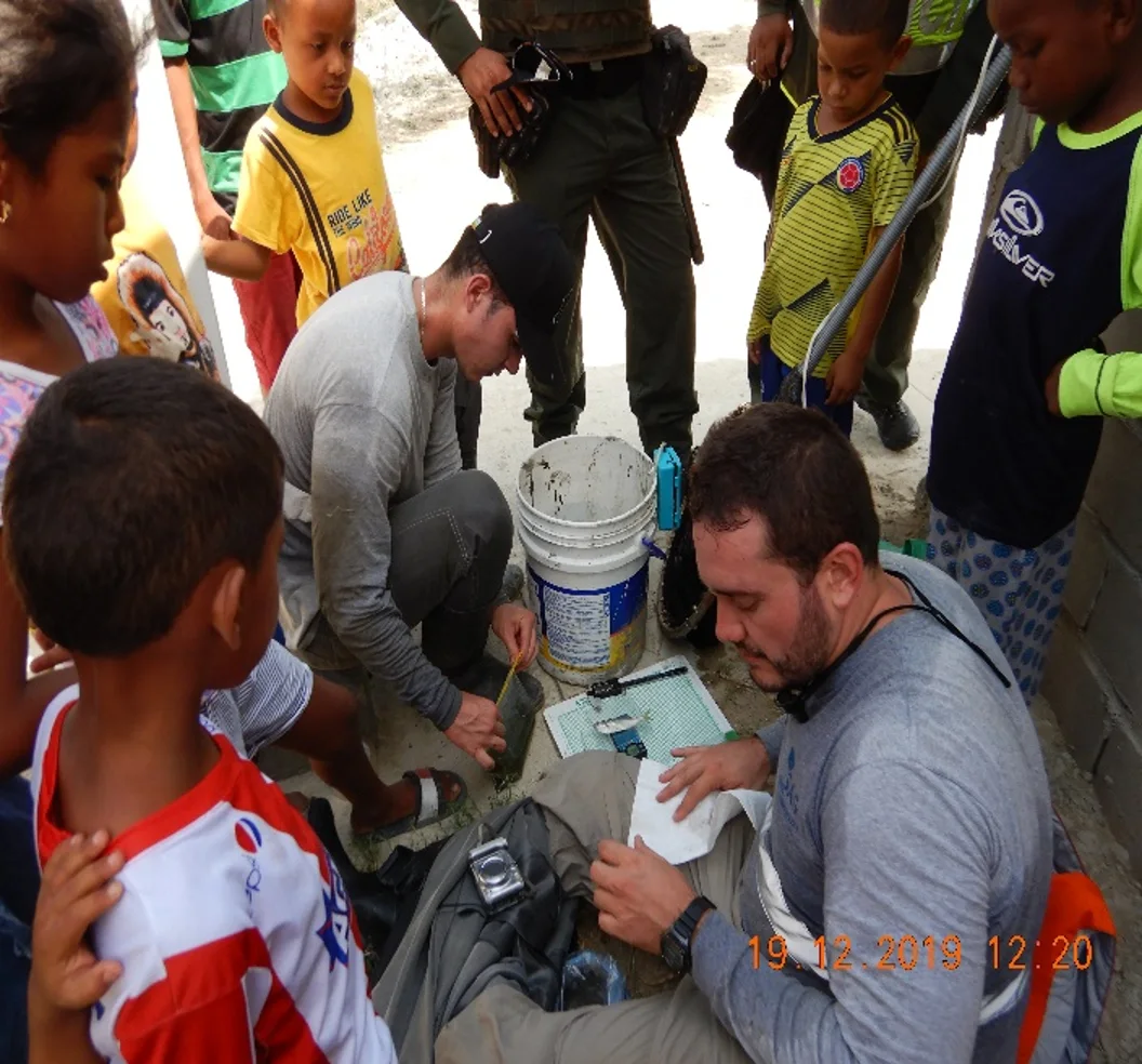 Group gathered around aquatic field sampling and field equipment.